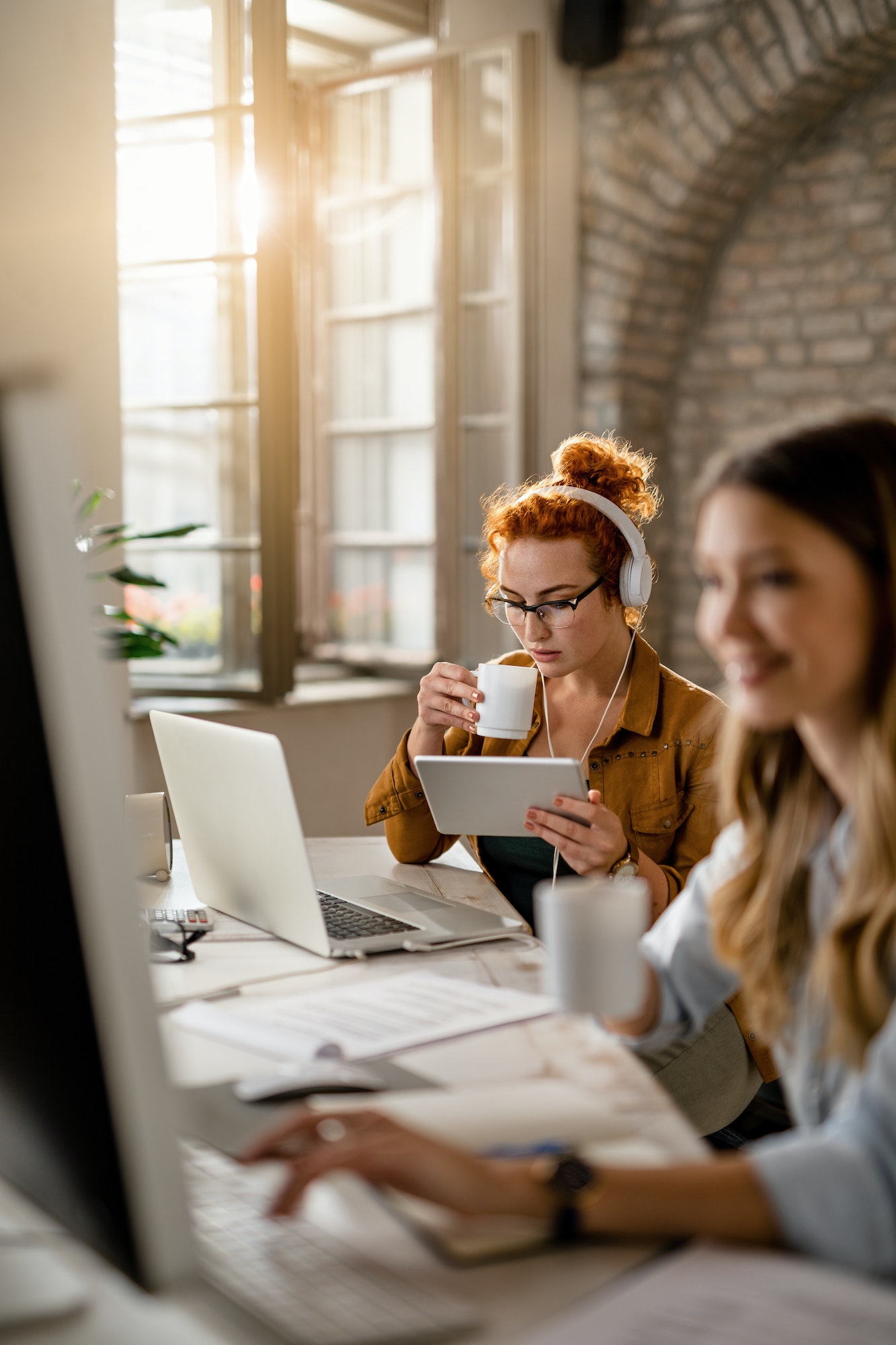 Female freelance worker drinking coffee while using digital tablet in the office.